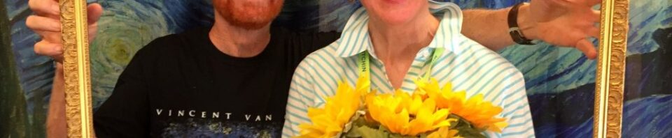 Couple posing with flowers in a picture frame.