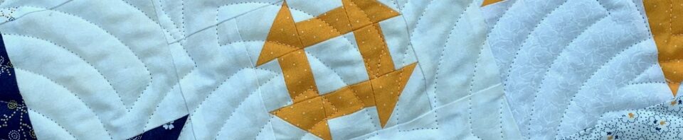 Colorful quilt with navy, white, and yellow patterns.