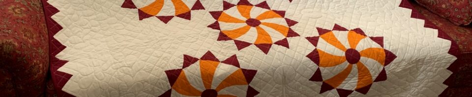 Colorful quilt draped over a patterned sofa.