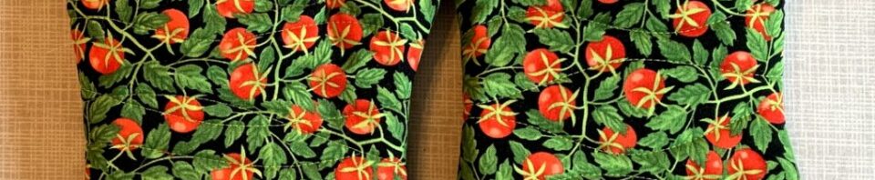 Colorful tomato-patterned oven mitts on table.