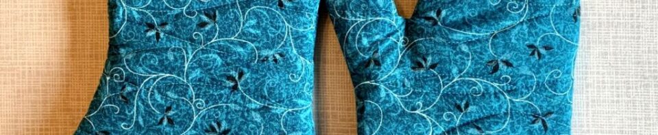 Blue patterned oven mitts on a light background.