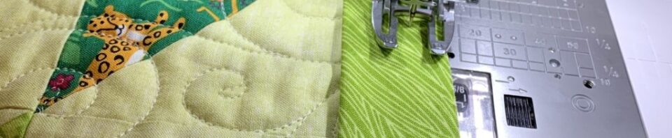 Quilting machine sewing green fabric patch.