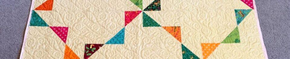 Colorful quilt with geometric patterns on cream.