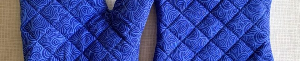 Blue patterned oven mitts with floral lining.