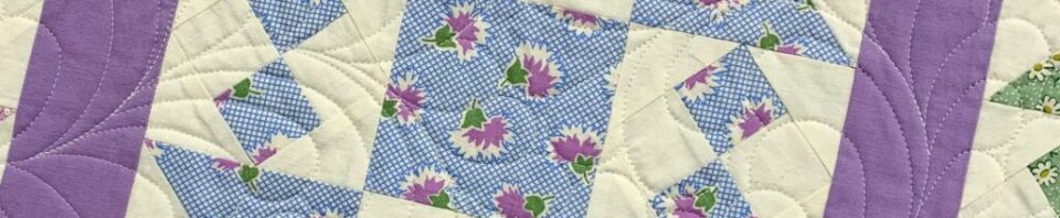 Colorful quilt featuring floral patterns and purple.