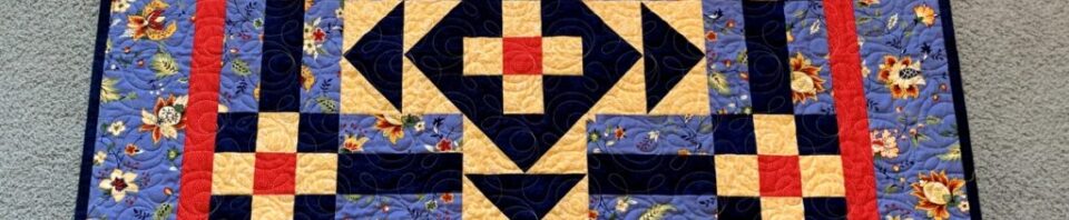 Colorful quilt with geometric patterns and floral border.