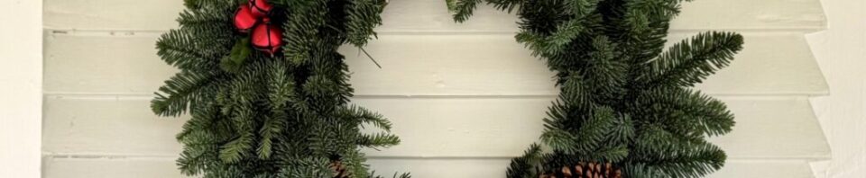 Christmas wreath with red accents and pinecones.